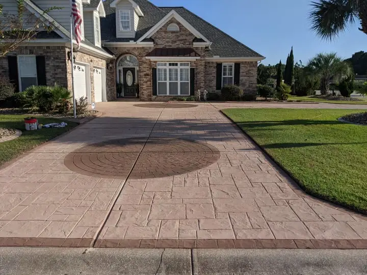A salmon stamped driveway with a circular medallion, photographed low along its length