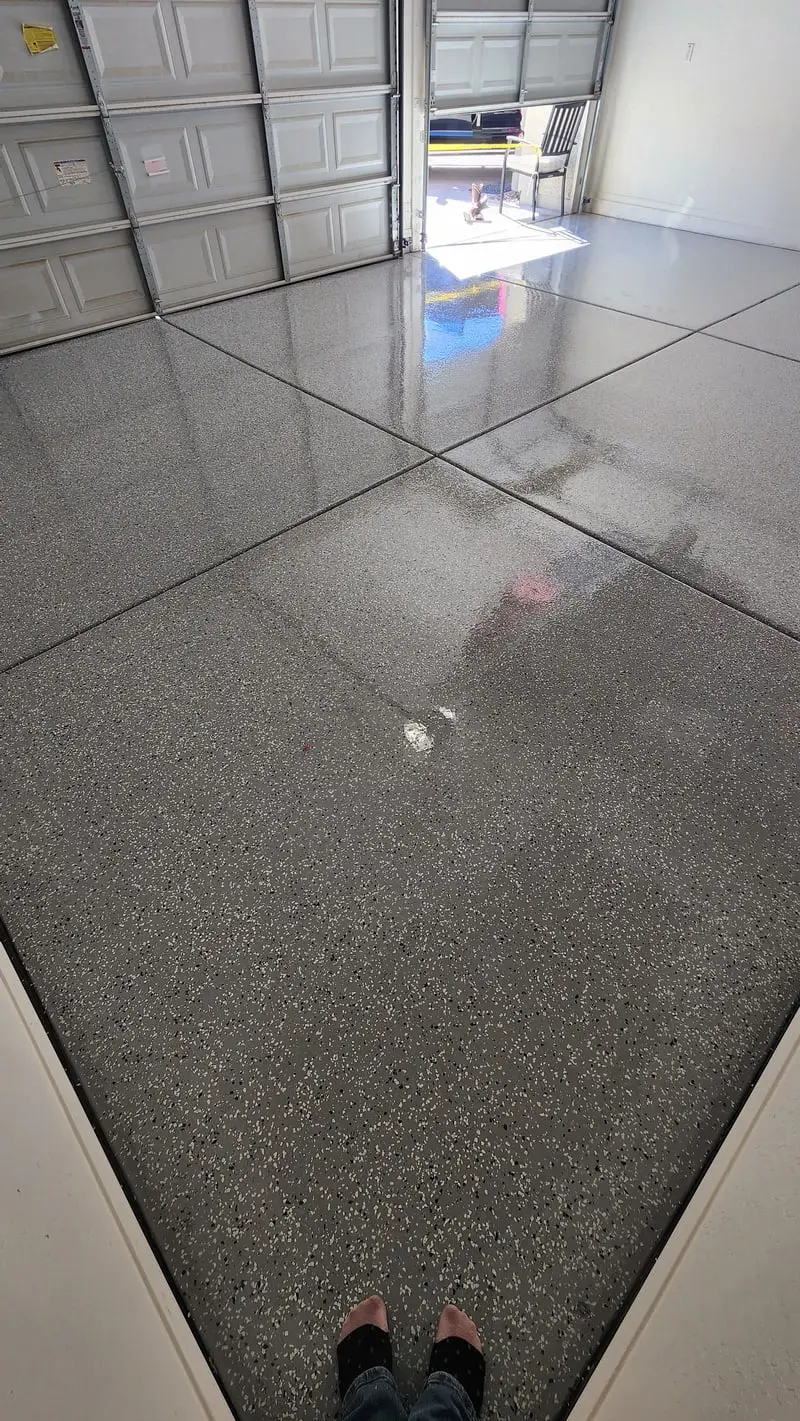 A glossy grey flake-epoxy garage floor reflecting the light from an open garage door
